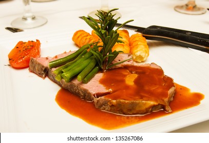 A Large Serving Of Prime Rib Beef With Gravy, Green Beans, Potatoes, Garnished With Rosemary