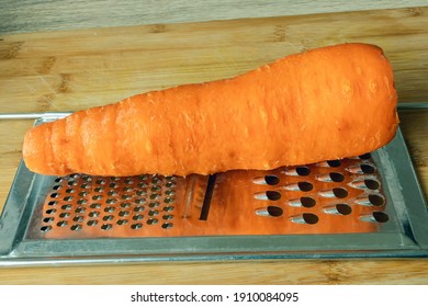 A Large Shaved Carrot With A Shredder On A Cutting Board