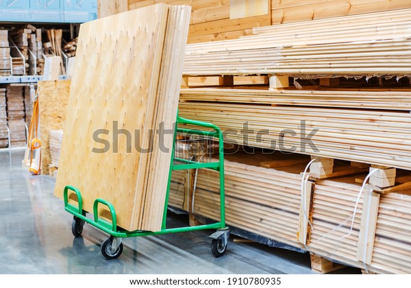 Large sheets of plywood lie on a\
transport cart in a building supplies store. Copy\
space