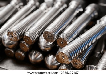 Large shiny bolts stack in plant warehouse macro view