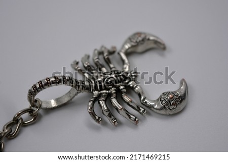 Large silver, metallic, militant figure of a scorpion located on a white background.  Zodiac sign scorpio, metal product, decoration - scorpio.