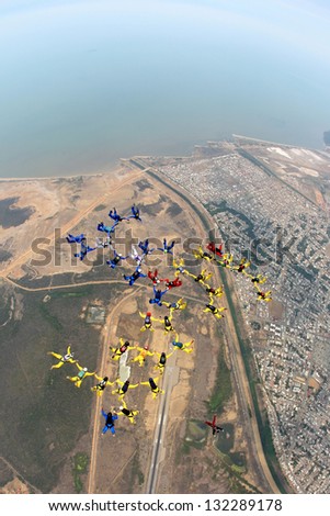 Large skydiving formation in free fall above a coastal beach