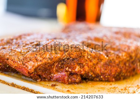 Large slab of meat seasoned ready to be cooked in smoker.