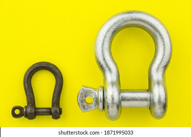 Large And Small Metal Rigging Shackle On Yellow Background. Professional Rigging Gear.