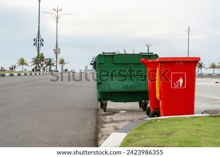Large and small recycling bins stand in an open city park in the harbor area. Indonesia, Tanjungpinang