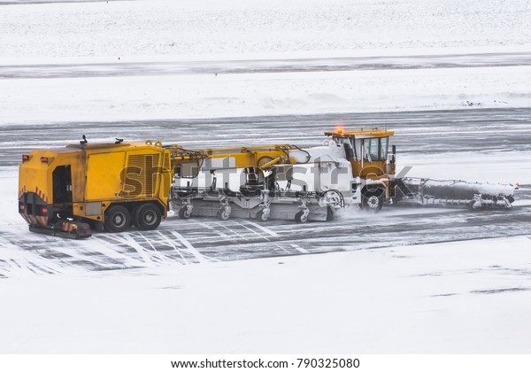 Large snow plowing machine at work on the road\
during a snow storm in\
winter