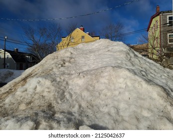 A Large Snowbank Blocking A View Of Buildings.