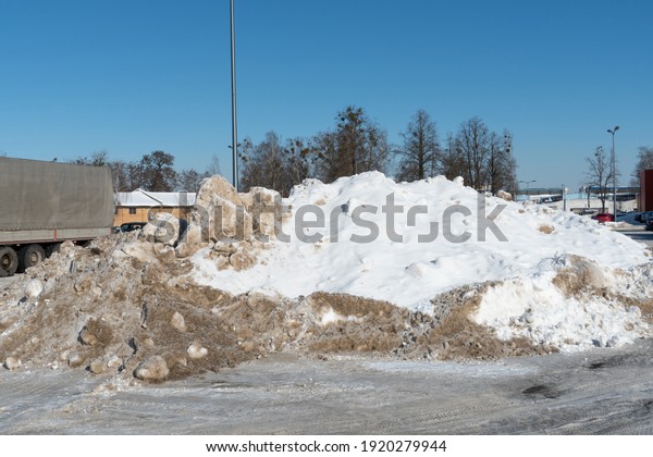 A large\
snowdrift in the parking lot. The truck in the parking lot got\
stuck in the snow. Cleaning roads from\
snow.