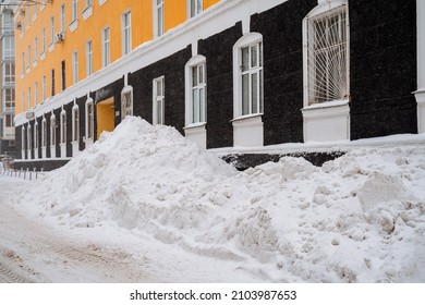Large snowdrifts in the city. Clearing snow debris. Snow removal on city streets. Utilities. Clean the snow. A large snowdrift is piled up. High quality photo