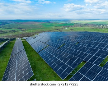 Large solar panel installation sits on green land under a clear sky. The sun shines on the panels while distant hills are visible. This area shows renewable energy use.