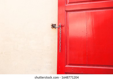 Large solid  RED wood door  was  tied by the Chains  to the old white cement wall  space   Vertical vintage  wallpaper  background texture