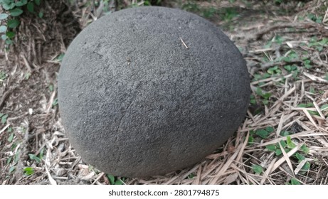Large spherical volcanic river stone sitting on dry ground