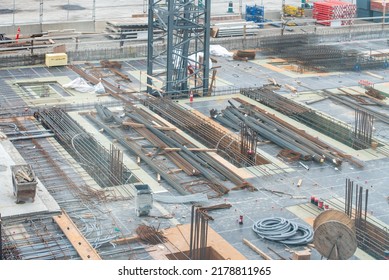 A Large Square Footage Of A Commercial Building With Concrete Forms, Rebar, And Electrical Wires. The Foundation Of The Skyrise Building Was Built. The Construction Site Has The Base Of A Crane.