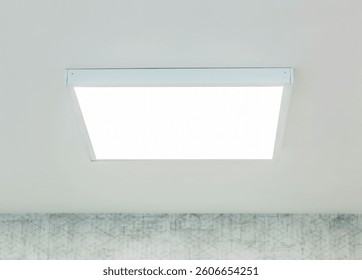 Large, square, led ceiling panel provides bright, even illumination in a contemporary room, enhancing visibility and creating a modern ambiance against a backdrop of patterned wallpaper