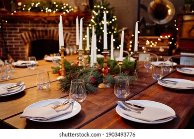 A Large Square Wooden Table Served For Christmas Dinner In A Country House With Large Windows. Evening Shooting. New Year With Friends And Family. The Interior Is Retro Styled. Low Light.