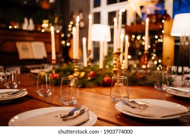 A Large Square Wooden Table Served For Christmas Dinner In A Country House With Large Windows. Evening Shooting. New Year With Friends And Family. The Interior Is Retro Styled. Low Light.