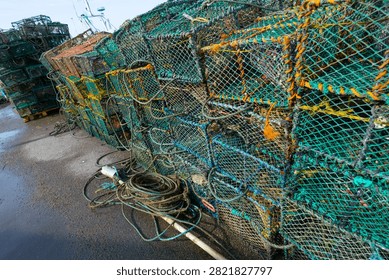 Large stack of lobster traps on pallet beside harbor fishing boats
