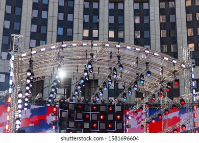 A Large Stage Is Located In The City. A Lot Of Spotlights. Preparing For The Show. Construction For Demonstration. Outdoor Concert Venue. Large-scale Concert. Sound And Lighting Equipment.