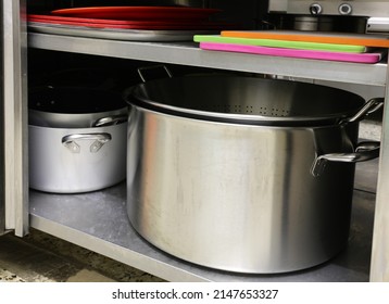 Large Stainless Steel Pot And Other Cookware And Cutting Boards Inside An Industrial Kitchen