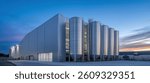 A large stainless steel tank with an industrial building in the background, close-up, blue sky, clean and bright, high-resolution photography, professional color grading, low contrast, soft shadows,