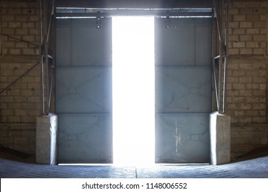 Large Steel Door Inside An Old Warehouse Opens Into An External Light. Concept Of Freedom.