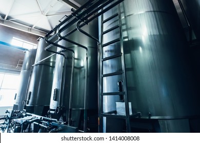 Large steel tanks or vats inside interior of juice and water production plant, blue toned