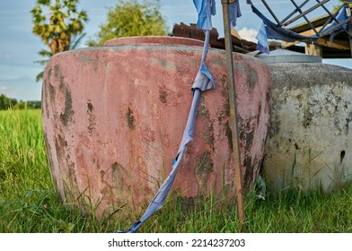 A Large Stone Water Jar In A Lush Green Field.