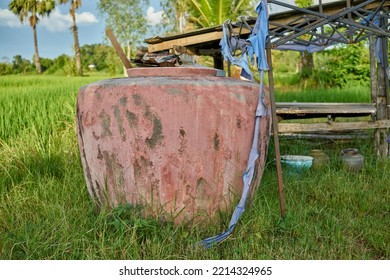 A Large Stone Water Jar In A Lush Green Field.