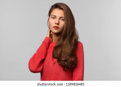 Large Studio portrait of a young beautiful girl in a red knitted sweater with long dark hair. Calm neutral expression, attentive gaze. - Powered by Shutterstock