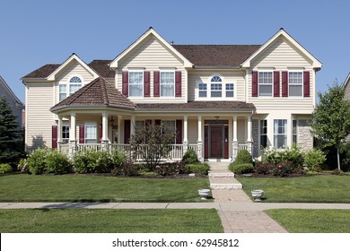 Large Suburban Home With Yellow Siding And Red Shutters