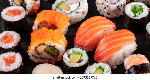 Large sushi set panoramic close-up on a black background. An assortment of various maki, nigiri and rolls - Powered by Shutterstock