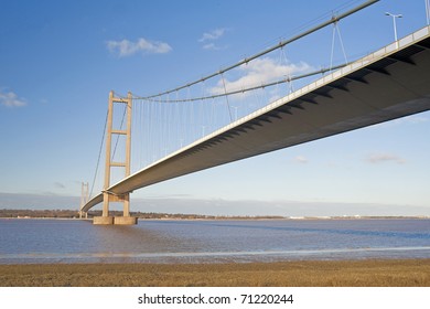 Large suspension bridge spanning a wide river on a clear day