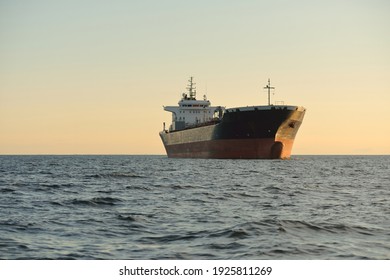 Large tanker ship sailing in an open sea at sunset. Golden sunlight. Freight transportation, fuel and power generation, nautical vessel, logistics, global communications, economy, business, industry
