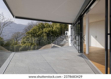 Large terrace of a new modern flat with a view of nature. The floor is made of stone.  