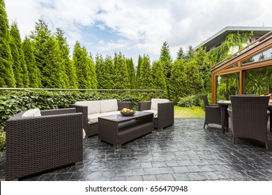 Large Terrace Patio With Rattan Garden Furniture Set Surrounded By Lush Greenery