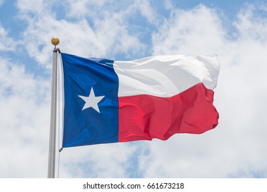 Large Texas (The Lone Star) Flag Waving On Flag Pole With Cloud Blue Sky. Windy And Sunny Day With Waving Flag Blowing/flowing. Ruffled Texas Flag. Room For Text, Copy Space.