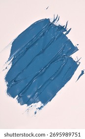 A large, textured, rectangular swipe of thick, matte blue paint is diagonally placed on a white surface
