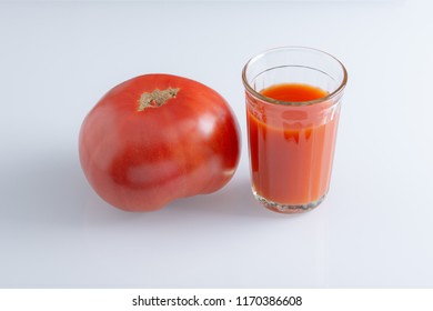 Large tomato and a glass of tomato juice