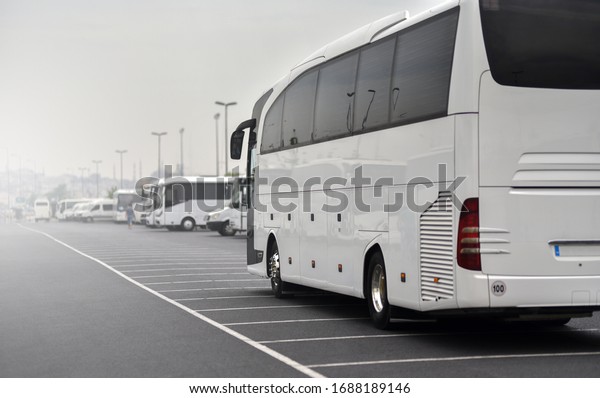 large tour bus\
rides along parked\
minibuses