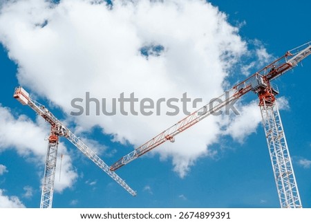 Large tower cranes on construction site with modern residential buildings. Industrial scene symbolizing growth, urban development, architecture, engineering, and city infrastructure progress.