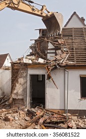 A Large Track Hoe Excavator Tearing Down An Old House