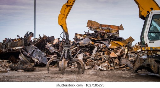 Large tracked excavator working a steel pile at a metal recycle yard, France - Shutterstock ID 1027185295