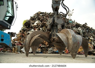 Large Tracked Excavator Working A Steel Pile At A Metal Recycle Yard. Industrial Scrap Metal Recycling - Selective Focus, Copy Space