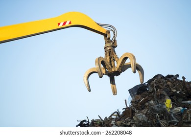 Large tracked excavator working a steel pile at a metal recycle yard - Powered by Shutterstock