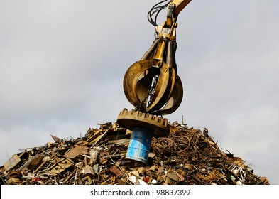 Large tracked excavator working a steel pile at a metal recycle yard with a magnet. - Powered by Shutterstock