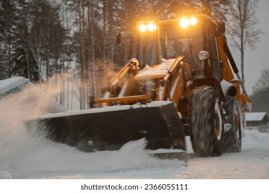 large tractor clearing the street after a snowfall in the suburbs, selective focus, blurred focus of construction equipment - Shutterstock ID 2366055111