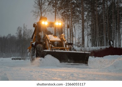 large tractor clearing the street after a snowfall in the suburbs, selective focus, blurred focus of construction equipment - Shutterstock ID 2366055117