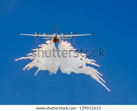 A large transport aircraft dispensing flares during a climb