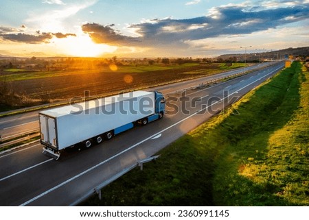 Large Transportation Truck on a highway road through the countryside in a beautiful sunset