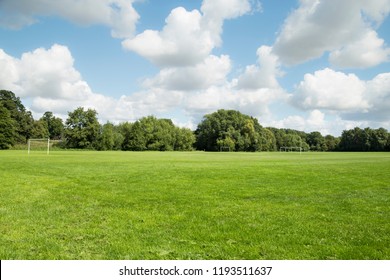 Large trimmed green grass soccer field with beautiful cloudy blue sky and copy space